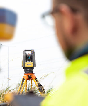 Topcon GT-700/1500 (premiera 2025 – najnowszy tachimetr) przewyższa starsze instrumenty: Prędkość i automatyzacja pracy: Starsze tachimetry: wolne serwomotory, ograniczona szybkość śledzenia i znajdowania pryzmatu. GT-700/1500: prędkość serwomotorów do 200°/s, system śledzenia UltraTrac™ → błyskawiczne znajdowanie pryzmatu. ? Efekt: szybsze tyczenie i pomiar, znaczące skrócenie czasu pracy w terenie. Stabilność pracy w trudnych warunkach: Starsze: łatwo gubiły pryzmat przy przeszkodach, serwomotory głośne i mniej wydajne. GT-700/1500: bezgłośne serwomotory BLDC o wysokiej wydajności zapewniają pewne działanie i wysoki komfort pracy. ? Efekt: niezawodność nawet w wymagającym otoczeniu. Praca jednoosobowa i kompaktowość: Starsze tachimetry na serwomotorach: często brak możliwości pracy jednoosobowej, wymagany był operator i pomocnik, a sprzęt miał duże gabaryty. GT-700/1500: najmniejszy tachimetr jednoosobowy na rynku, z możliwością pracy jednoosobowej lub w trybie Hybrid Positioning™ (GNSS + tachimetr). ? Efekt: oszczędność kosztów i czasu oraz większa mobilność w terenie. Precyzja i bezpieczeństwo inwestycji: Starsze: niższa częstotliwość dalmierza - zwykle 1Hz krótsze okresy gwarancji, brak nowoczesnych zabezpieczeń. GT-700/1500: częstotliwość 10 Hz – szybsze i dokładniejsze tyczenie oraz 36 miesięcy gwarancji + 60 miesięcy na serwomotory. ? Efekt: pewne wyniki i gwarancja niezawodności oraz długowieczności sprzętu.