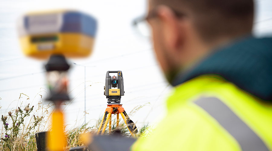 Topcon GT-700/1500 (premiera 2025 – najnowszy tachimetr) przewyższa starsze instrumenty: Prędkość i automatyzacja pracy: Starsze tachimetry: wolne serwomotory, ograniczona szybkość śledzenia i znajdowania pryzmatu. GT-700/1500: prędkość serwomotorów do 200°/s, system śledzenia UltraTrac™ → błyskawiczne znajdowanie pryzmatu. 👉 Efekt: szybsze tyczenie i pomiar, znaczące skrócenie czasu pracy w terenie. Stabilność pracy w trudnych warunkach: Starsze: łatwo gubiły pryzmat przy przeszkodach, serwomotory głośne i mniej wydajne. GT-700/1500: bezgłośne serwomotory BLDC o wysokiej wydajności zapewniają pewne działanie i wysoki komfort pracy. 👉 Efekt: niezawodność nawet w wymagającym otoczeniu. Praca jednoosobowa i kompaktowość: Starsze tachimetry na serwomotorach: często brak możliwości pracy jednoosobowej, wymagany był operator i pomocnik, a sprzęt miał duże gabaryty. GT-700/1500: najmniejszy tachimetr jednoosobowy na rynku, z możliwością pracy jednoosobowej lub w trybie Hybrid Positioning™ (GNSS + tachimetr). 👉 Efekt: oszczędność kosztów i czasu oraz większa mobilność w terenie. Precyzja i bezpieczeństwo inwestycji: Starsze: niższa częstotliwość dalmierza - zwykle 1Hz krótsze okresy gwarancji, brak nowoczesnych zabezpieczeń. GT-700/1500: częstotliwość 10 Hz – szybsze i dokładniejsze tyczenie oraz 36 miesięcy gwarancji + 60 miesięcy na serwomotory. 👉 Efekt: pewne wyniki i gwarancja niezawodności oraz długowieczności sprzętu.
